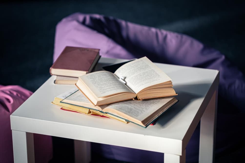 Open and closed books lie on a white table against a dark background