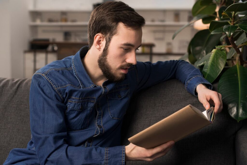 Man sitting on couch and reading book